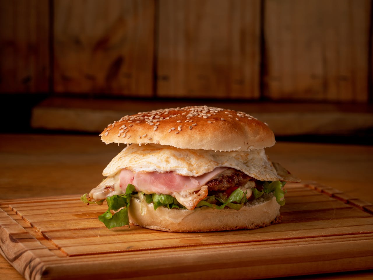 services-02 Close-up of a mouthwatering burger with egg on a wooden board, perfect for fast food lovers.