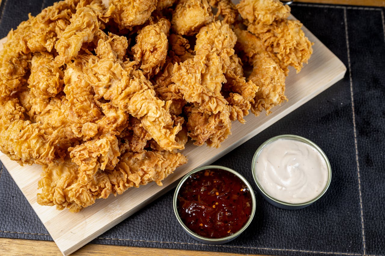 services-03 Delicious golden fried chicken tenders served with spicy and creamy dipping sauces on a platter.